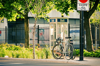 Bicycle parked on sidewalk near vintage Bell phone booth