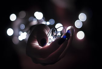 Hand holding glowing fairy lights with bokeh background