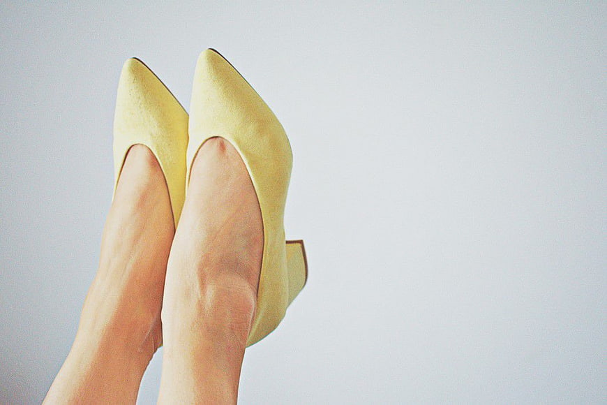 Woman's Feet in Yellow Heels Against White Background