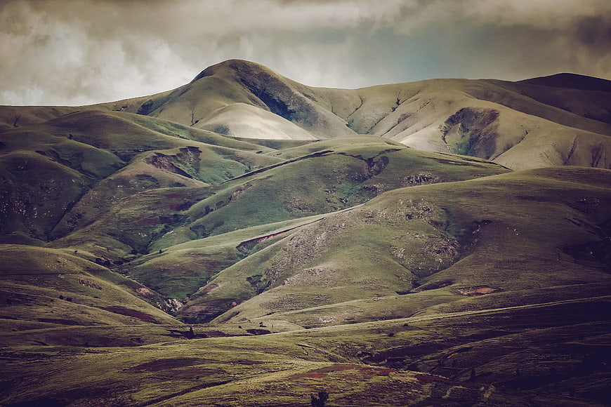 Dramatic rolling green hills under moody cloudy sky