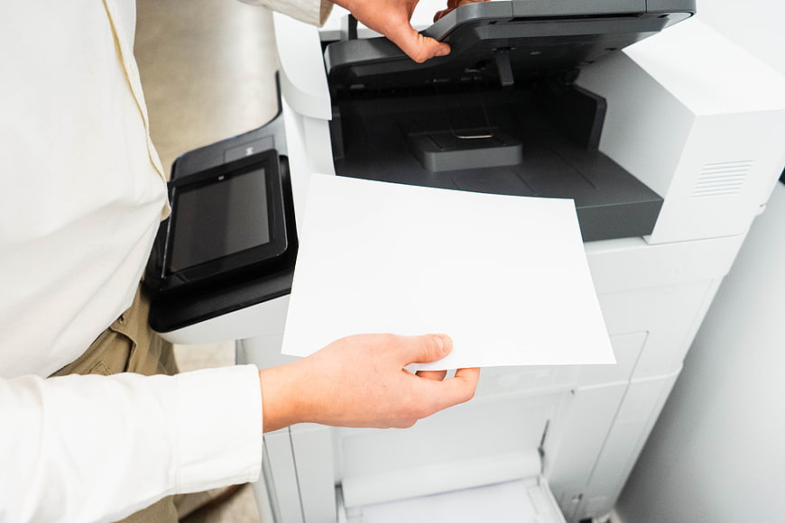 Person Using Office Copier Machine with Blank Paper