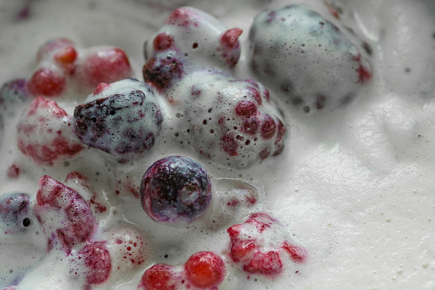 Close-up of mixed berries in frothy white cream