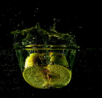 Lime Slices Splashing in Water on Black Background