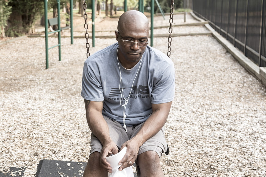 Depressed Black Man Sitting On Playground Swing