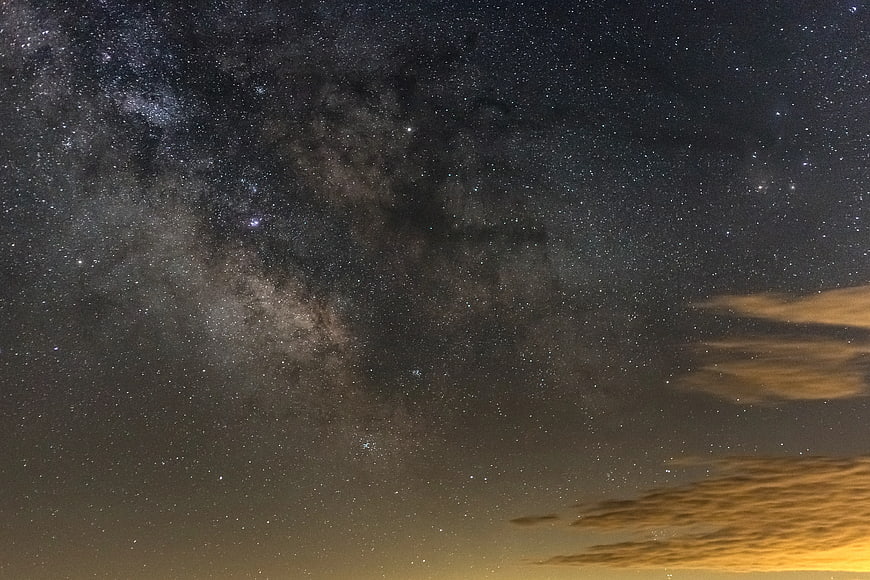 Milky Way galaxy night sky with illuminated clouds