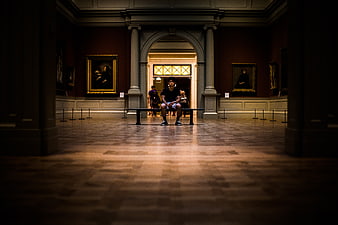 Man sitting alone on bench in grand museum gallery