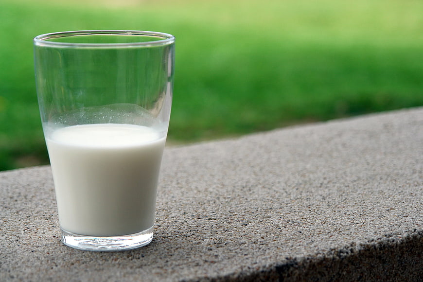 Glass of Fresh Milk on Concrete with Green Background