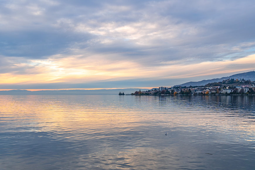 Serene Lake Geneva Sunset With Montreux Townscape And Cloudy Sky