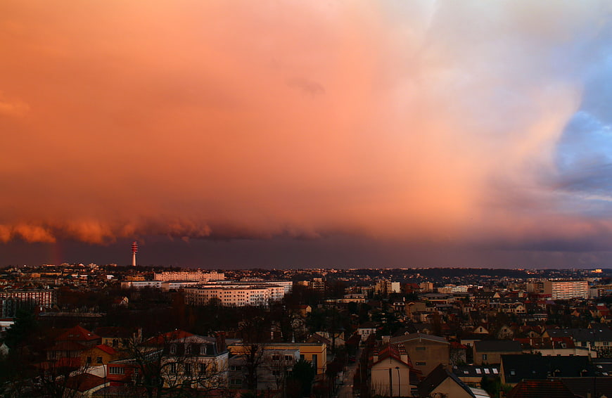 Dramatic sunset over city skyline with storm clouds and rainbow