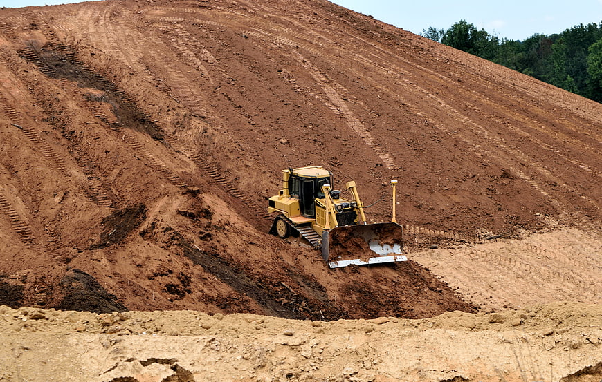 Yellow Bulldozer Grading Earth on Construction Site