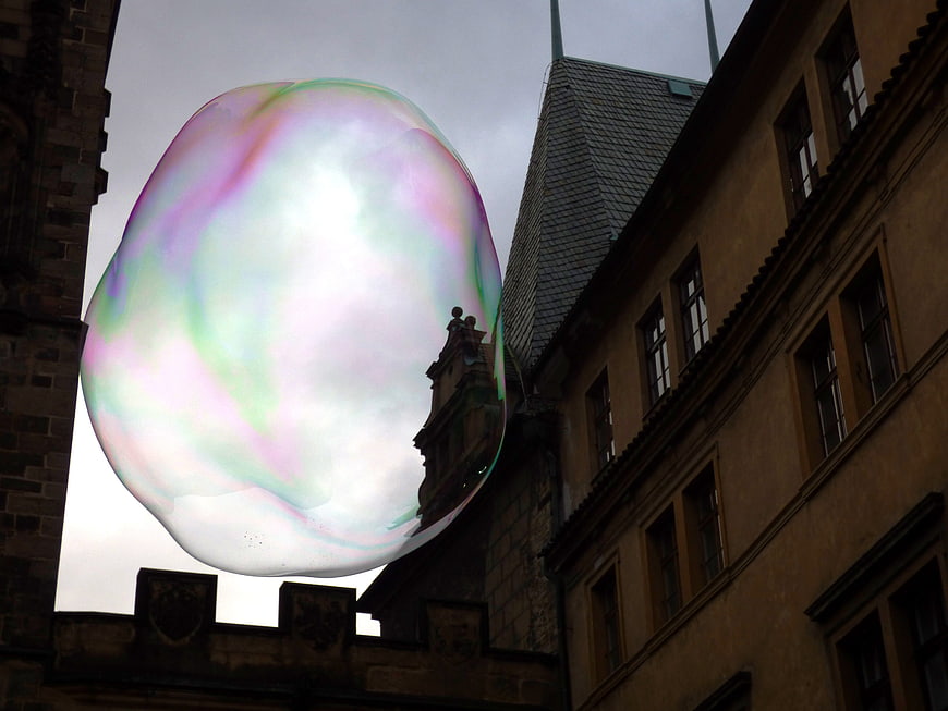 Giant iridescent soap bubble reflecting historic European architecture