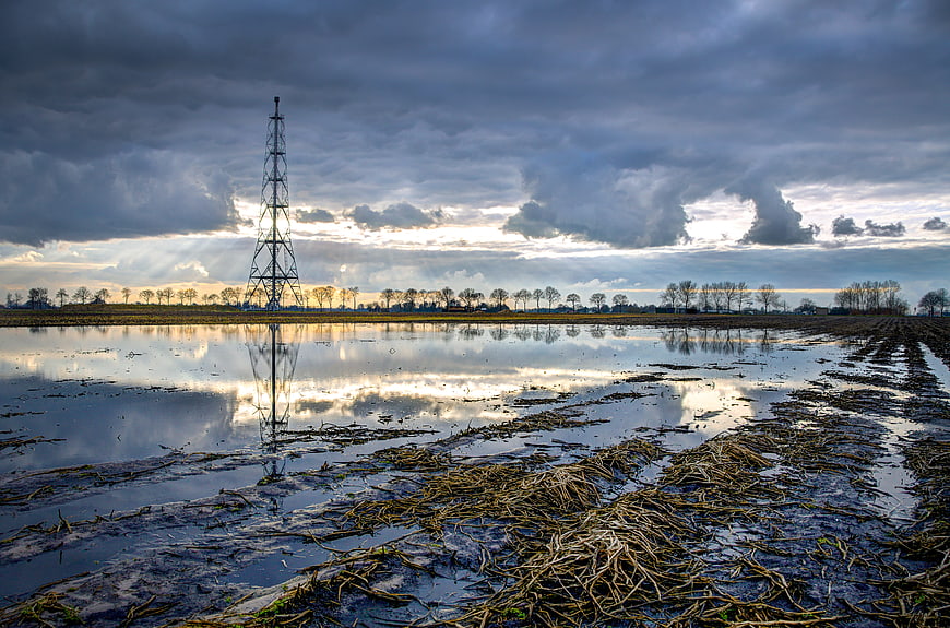 Dramatic landscape with gas tower and flooded field reflection