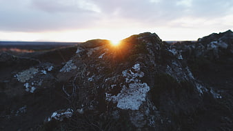 Sunset Behind Mossy Rock in Rugged Landscape