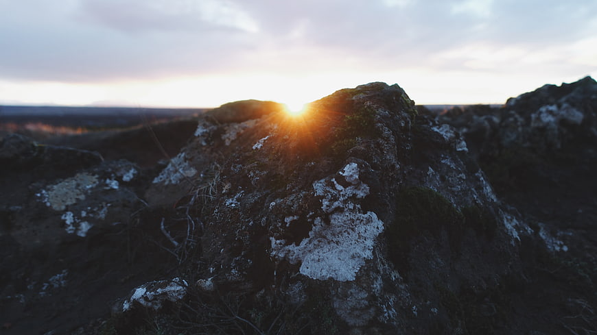 Sunset Behind Mossy Rock in Rugged Landscape