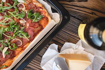 Homemade pizza with arugula, cheese, and wine on wooden table