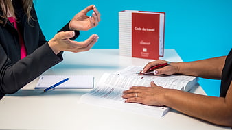 Businesswomen discussing labor code and legal documents at a desk