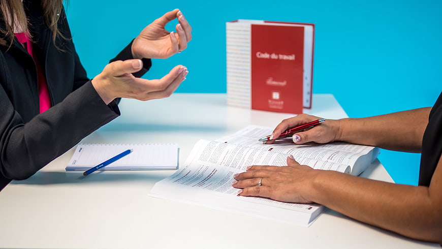 Businesswomen discussing labor code and legal documents at a desk