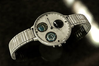 Silver luxury wristwatch with globe subdials on dark background
