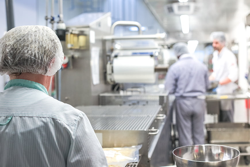 Back view of chef in hairnet working in commercial kitchen