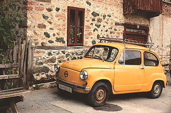 Vintage yellow car parked in front of rustic stone house