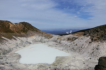 Milky white volcanic crater lake in mountainous landscape