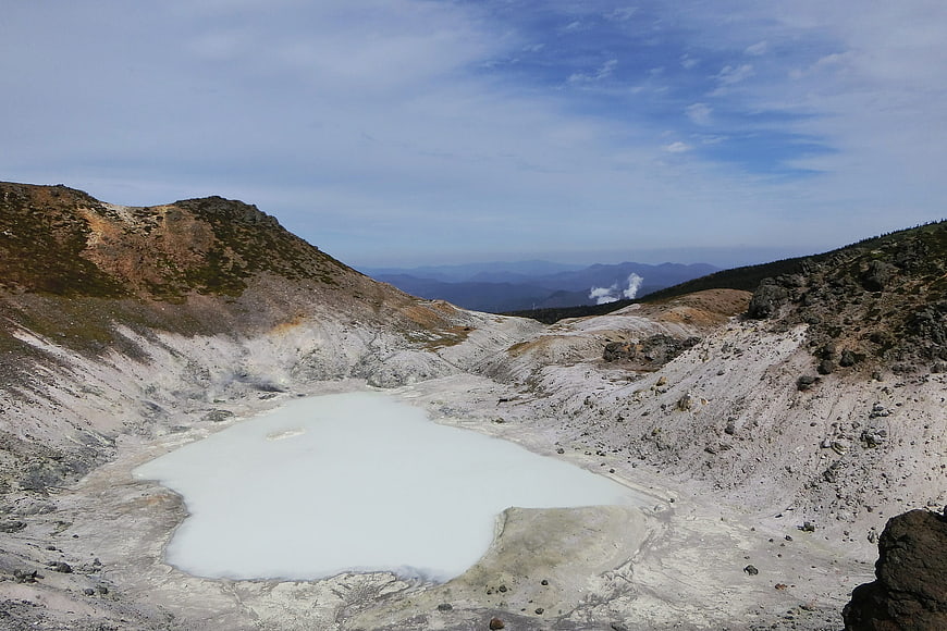 Milky white volcanic crater lake in mountainous landscape