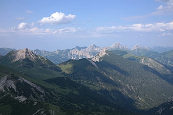Panoramic Alpine Mountain Landscape with Green Slopes and Blue Sky