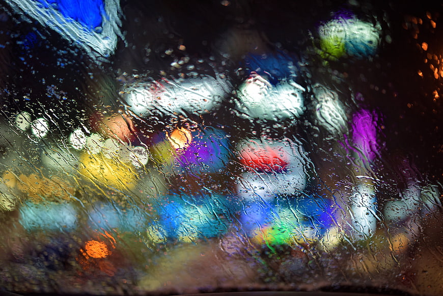 Abstract Bokeh Lights Through Rainy Window Glass at Night