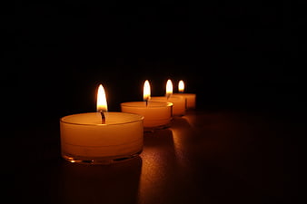 Row of lit tea light candles on dark background