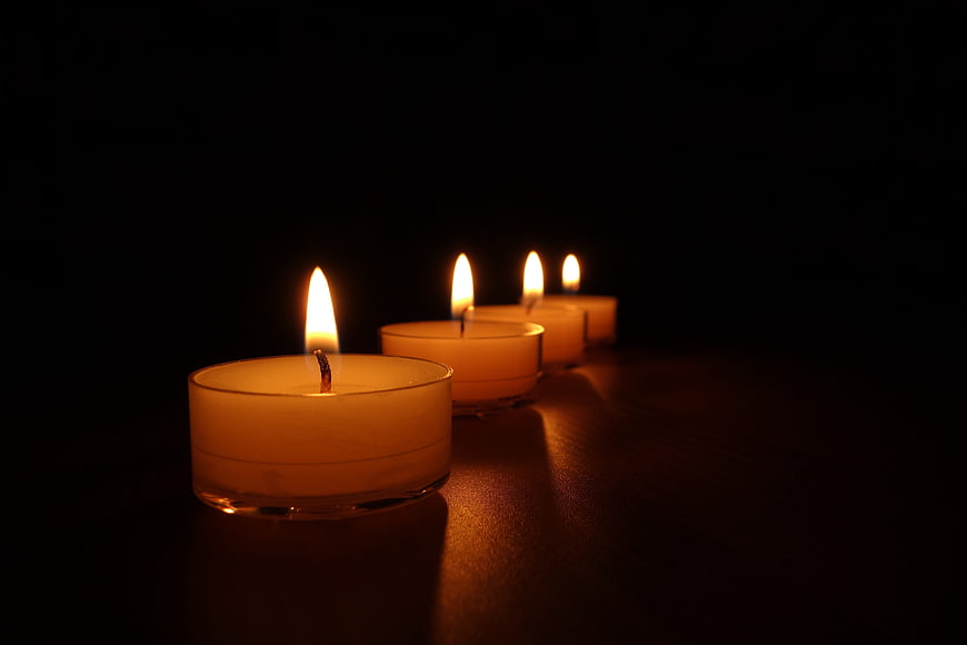 Row of lit tea light candles on dark background