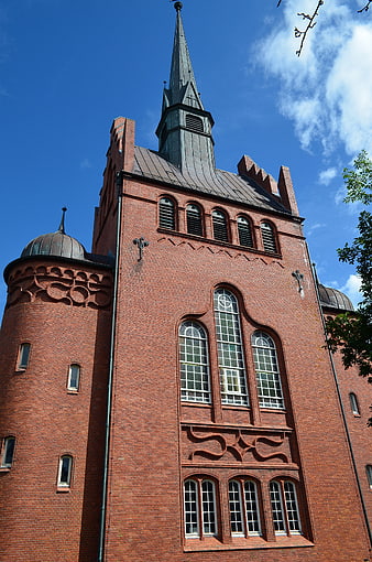 Low angle view of red brick church tower against blue sky