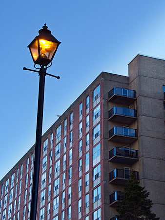 Vintage Street Lamp Glowing Against Blue Sky and Apartment Building