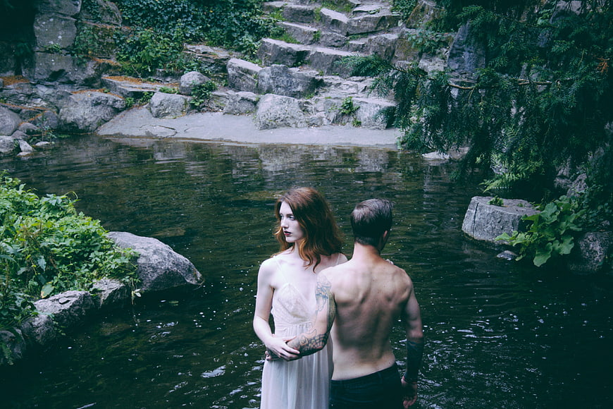 Couple standing in river with woman looking back