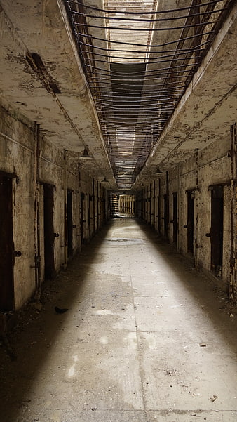 Derelict Prison Corridor With Peeling Walls And Rusty Metal Grating