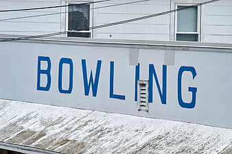 Vintage Blue Bowling Sign on Weathered White Building Exterior