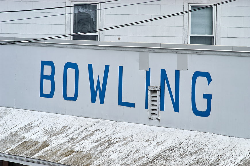 Vintage Blue Bowling Sign on Weathered White Building Exterior