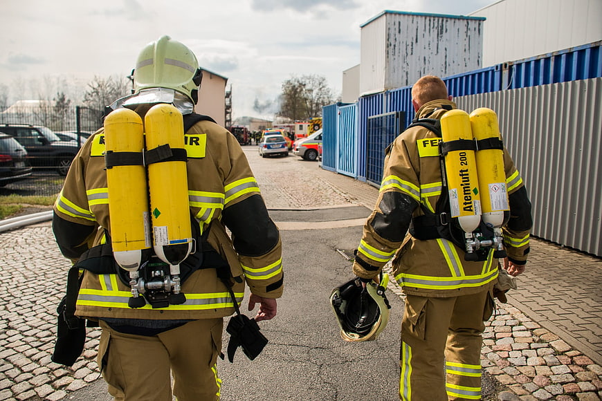 Two Firefighters Walking Away With Yellow Air Tanks