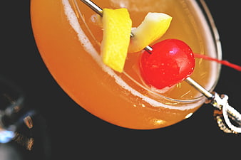 Close-up of orange cocktail with lemon and cherry garnish