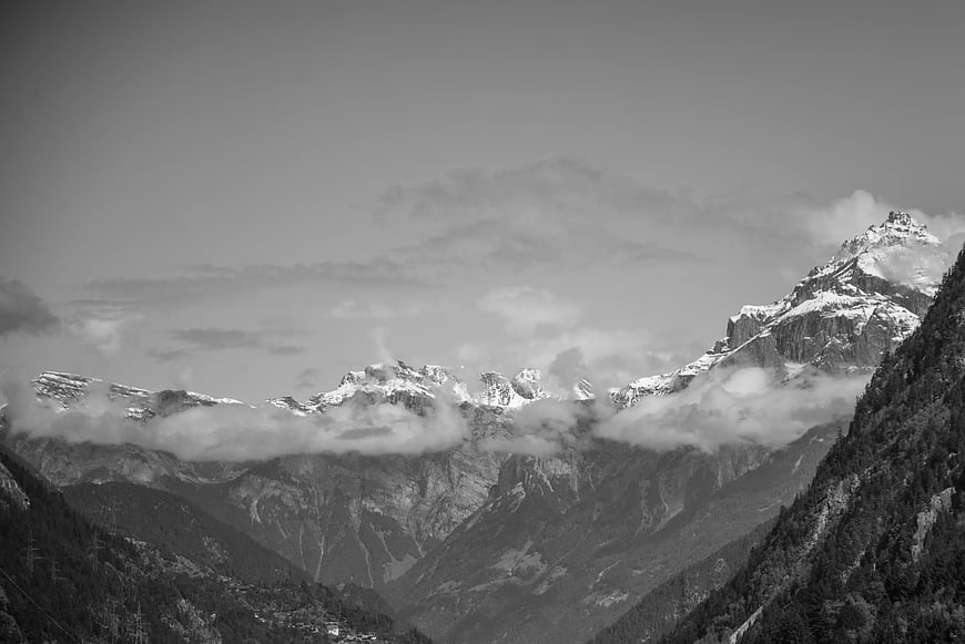 Black and white snow-covered rugged mountain peaks with mist