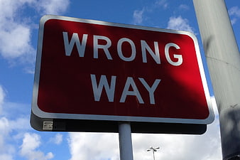 Red Wrong Way Traffic Sign Against Blue Sky