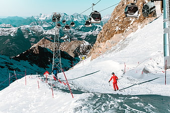 Skier in Red Suit on Mountain Slope with Cable Cars