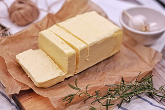 Sliced butter block on parchment paper with fresh rosemary sprigs