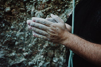 Rock climber chalking hands against textured rock wall