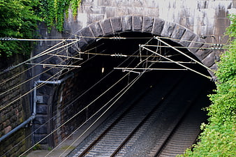 Stone railway tunnel entrance with overhead electric wires