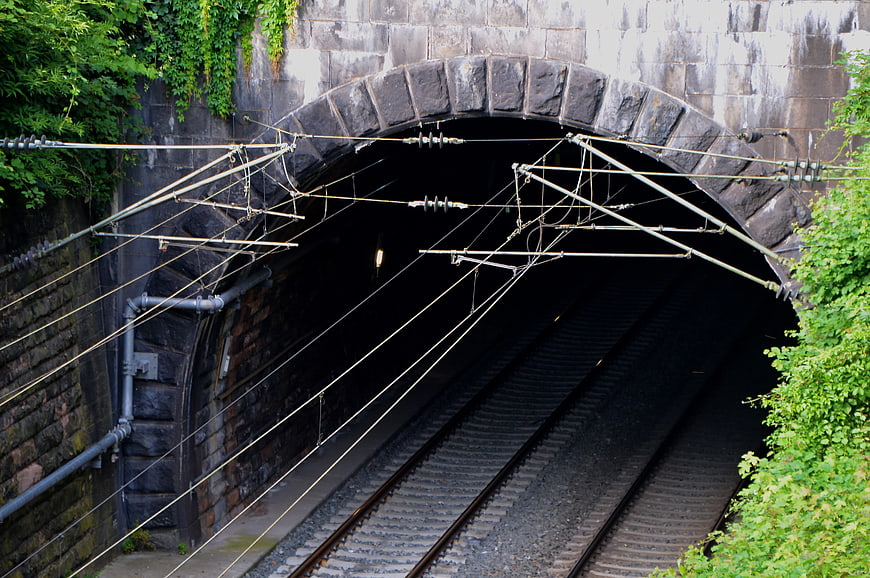 Stone railway tunnel entrance with overhead electric wires