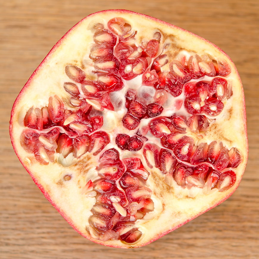 Fresh cut pomegranate cross section on wooden background