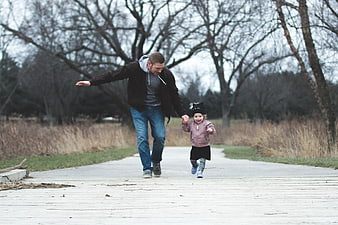 Father and Toddler Running Hand in Hand on Park Path