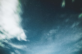 Starry night sky with wispy clouds and blue tones