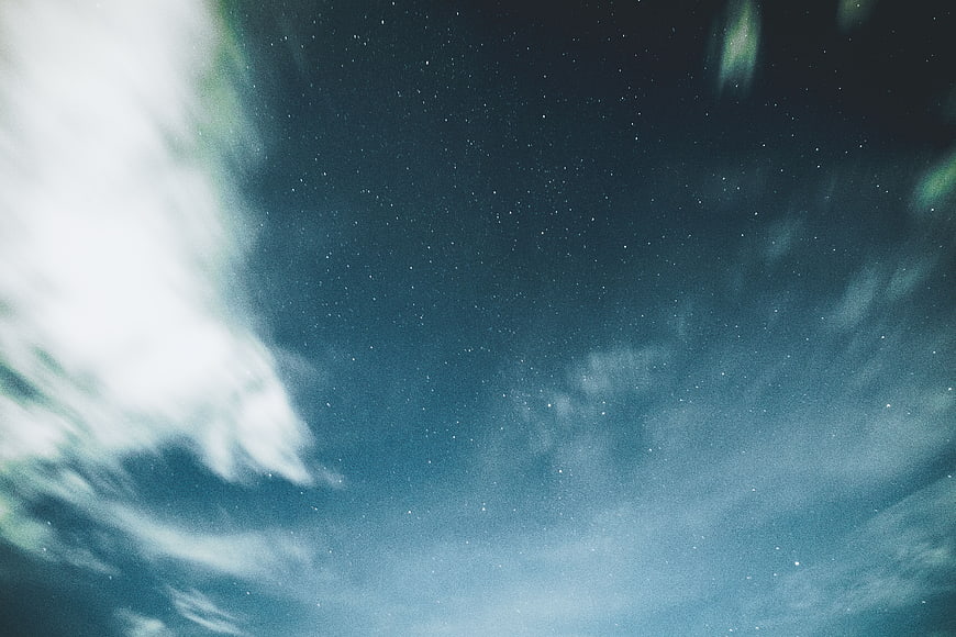 Starry night sky with wispy clouds and blue tones