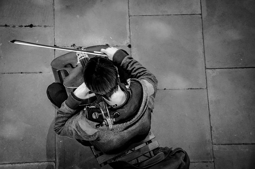 High angle black and white photo of street musician playing cello